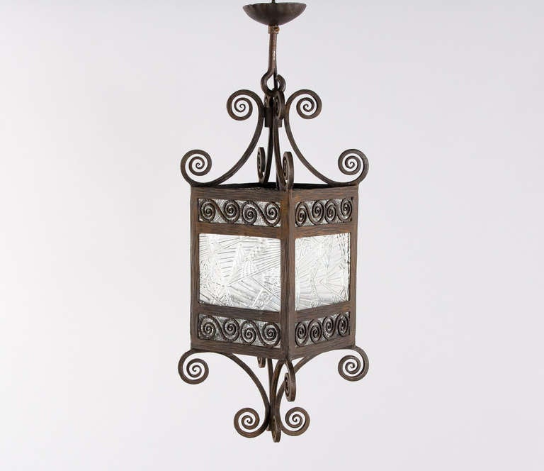 A small French Art Deco Lantern in scrolled forged iron from the 1930's. The light fixture has etched glass panels with geometrical designs and holds one standard size light bulb. Perfect for a foyer, small room or a patio. Rewired to US Standards.
