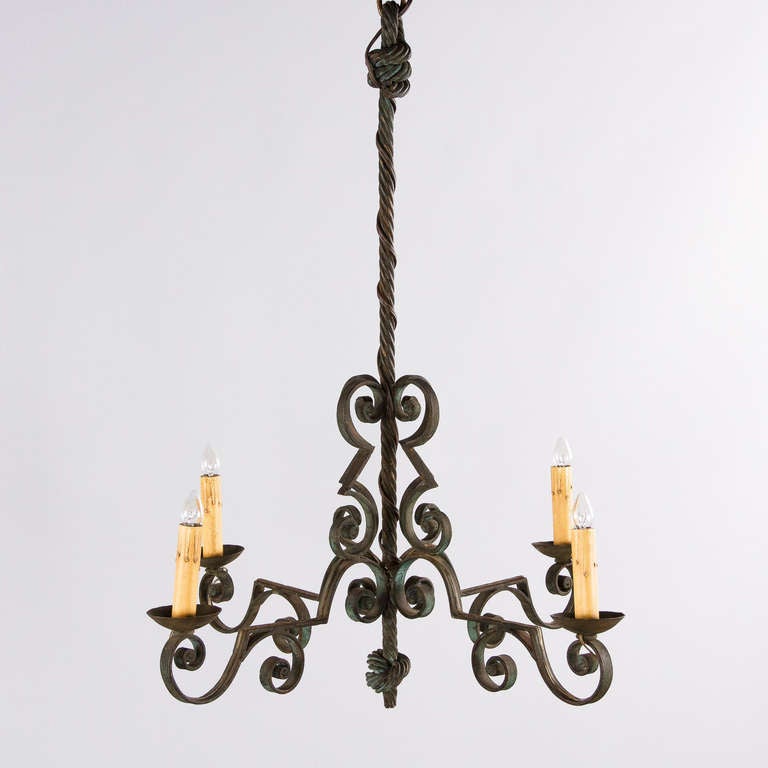 This French wrought iron chandelier is made of forged iron with a lovely green patina. With four lights, this chandelier has a twisted rope center rod finished off with scrolled arms. Note: Two matching sconces are also available.