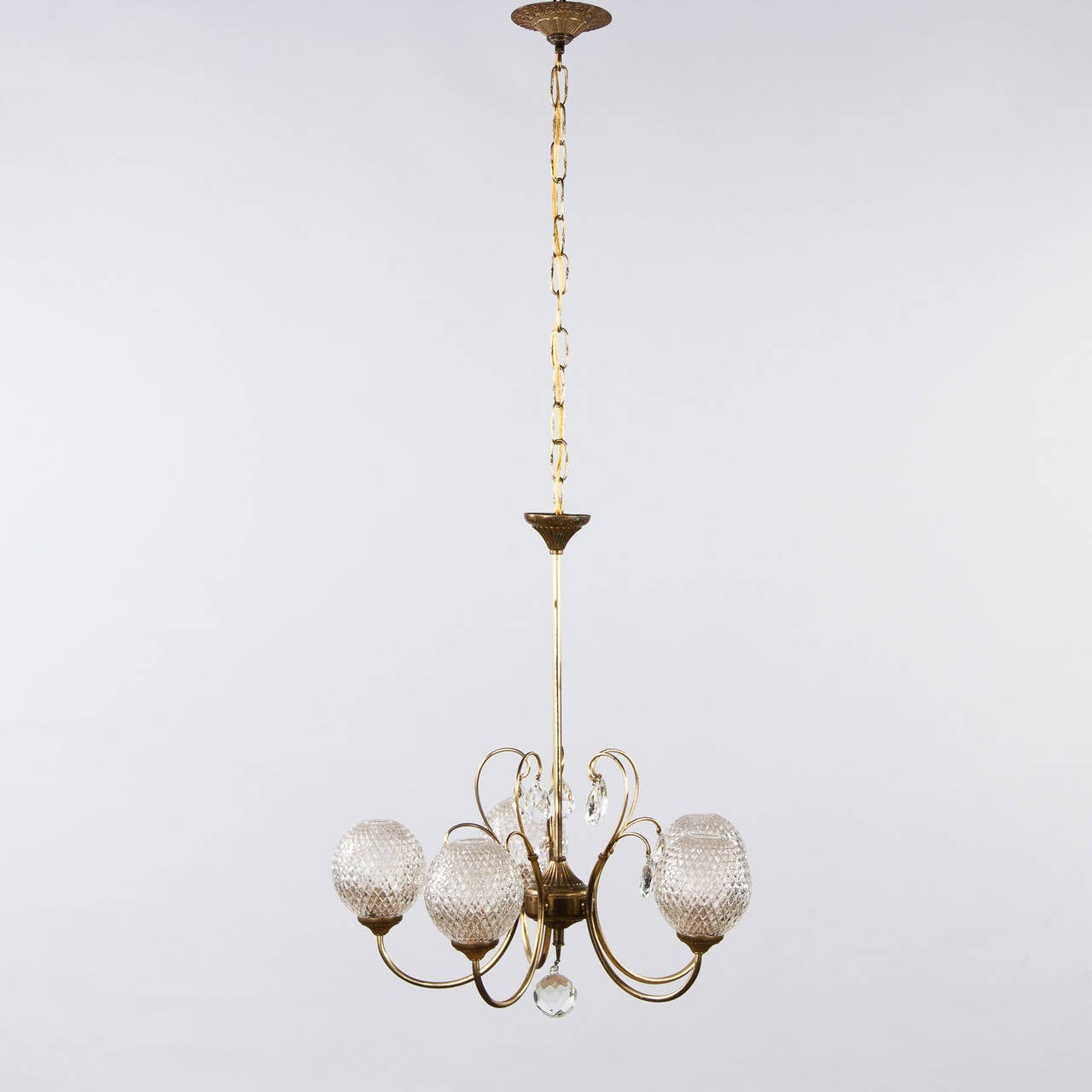 A 1950s French chandelier made of brass with crystal pendants and housing five lights inside etched glass globes. The new adjustable chain and canopy add 23