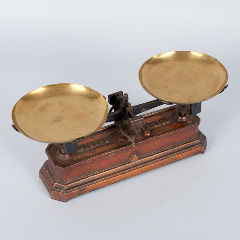 A decorative Apothecary Scale in burnt orange enamelled metal with brass plateaux.