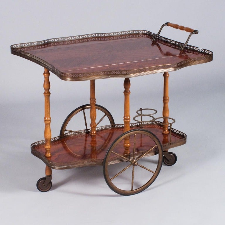 An early 1900's two-tiered Bar Cart in beautiful rosewood veneer with fruit wood inlaid and flower motif marquetry. The top plateau has two drop leaves and a brass galleried edge.  The bottom shelf also has a galleried edge and a three bottle brass