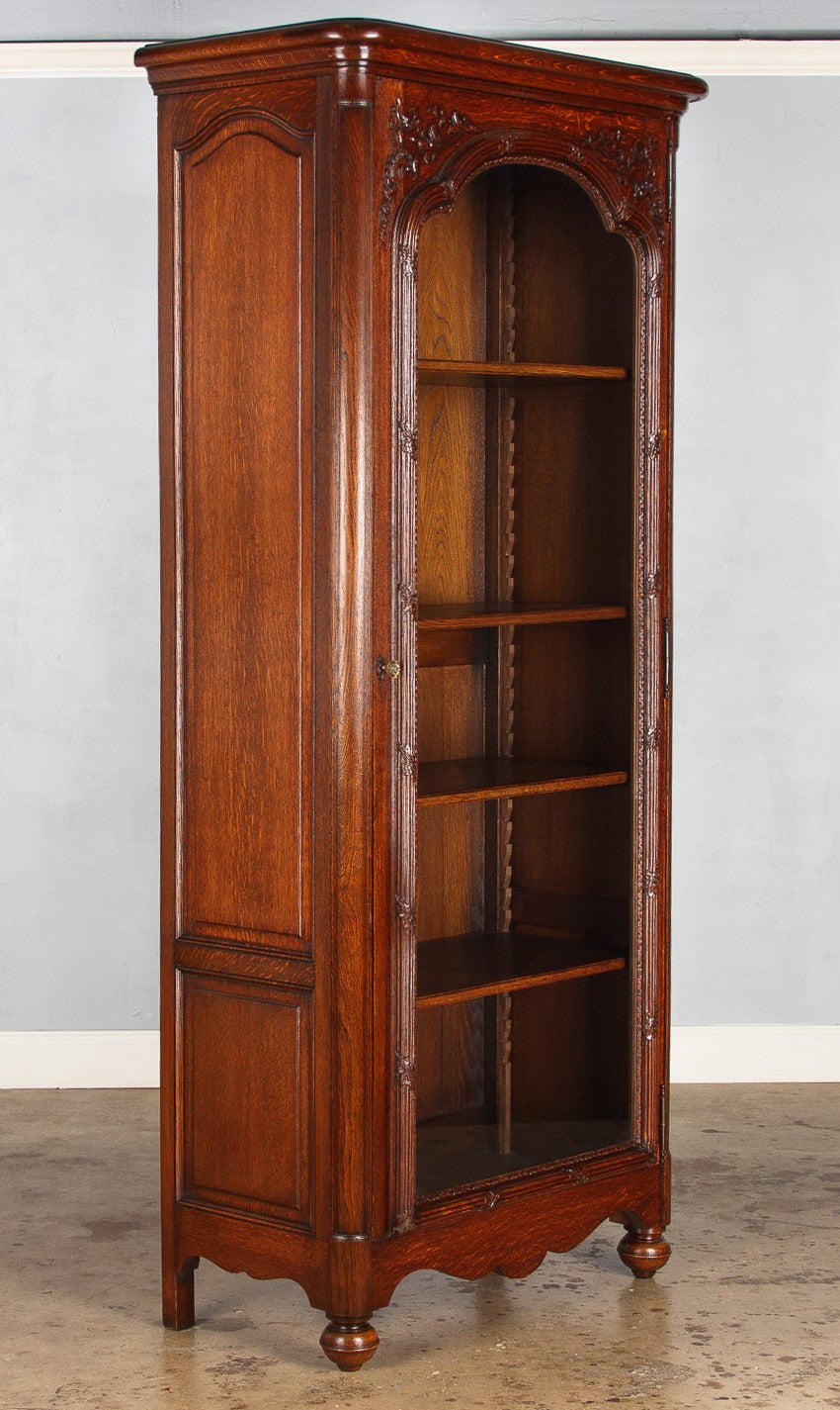 A wonderful vitrine or bookcase from the Napoleon III period made in Paris in the late 1800s. The vitrine is make of oak with a scalloped apron, paneled sides and rests on bun feet. The glass door features a raised edge with fascia molding and