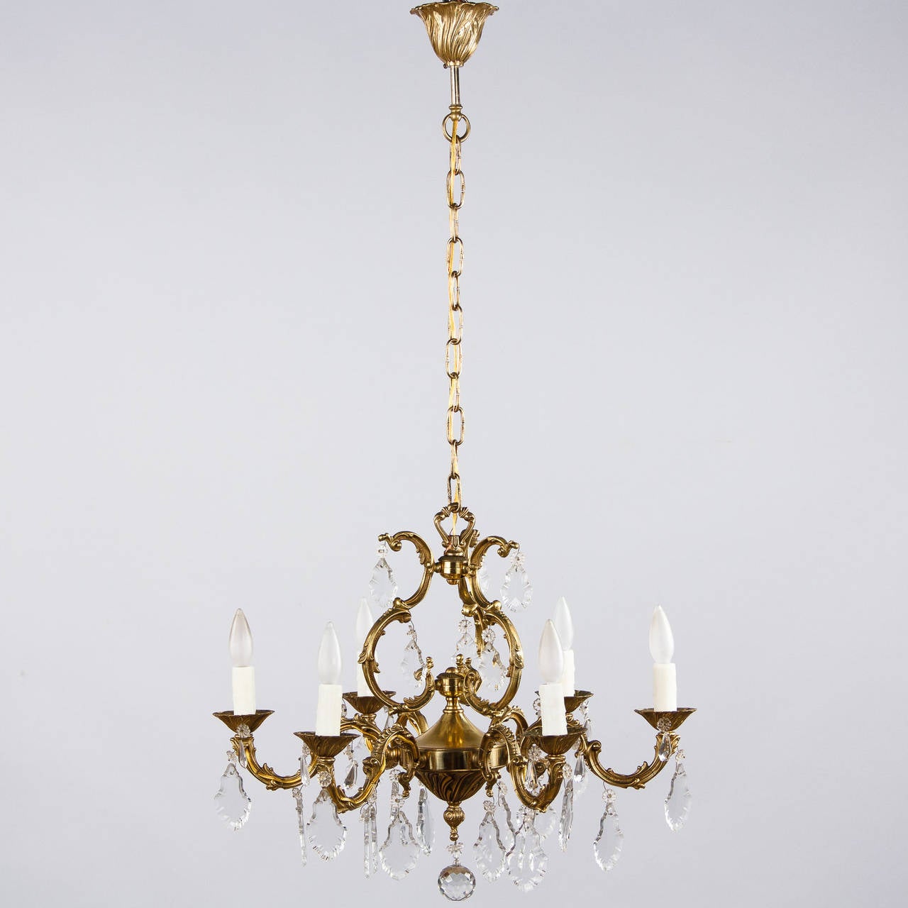 A 6 arm Louis XV Style Chandelier made of sculpted gilded bronze with scrolls and arabesques. Each arm features crystal pendants and the bottom center is finished with a crystal ball. The adjustable chain and canopy add 24