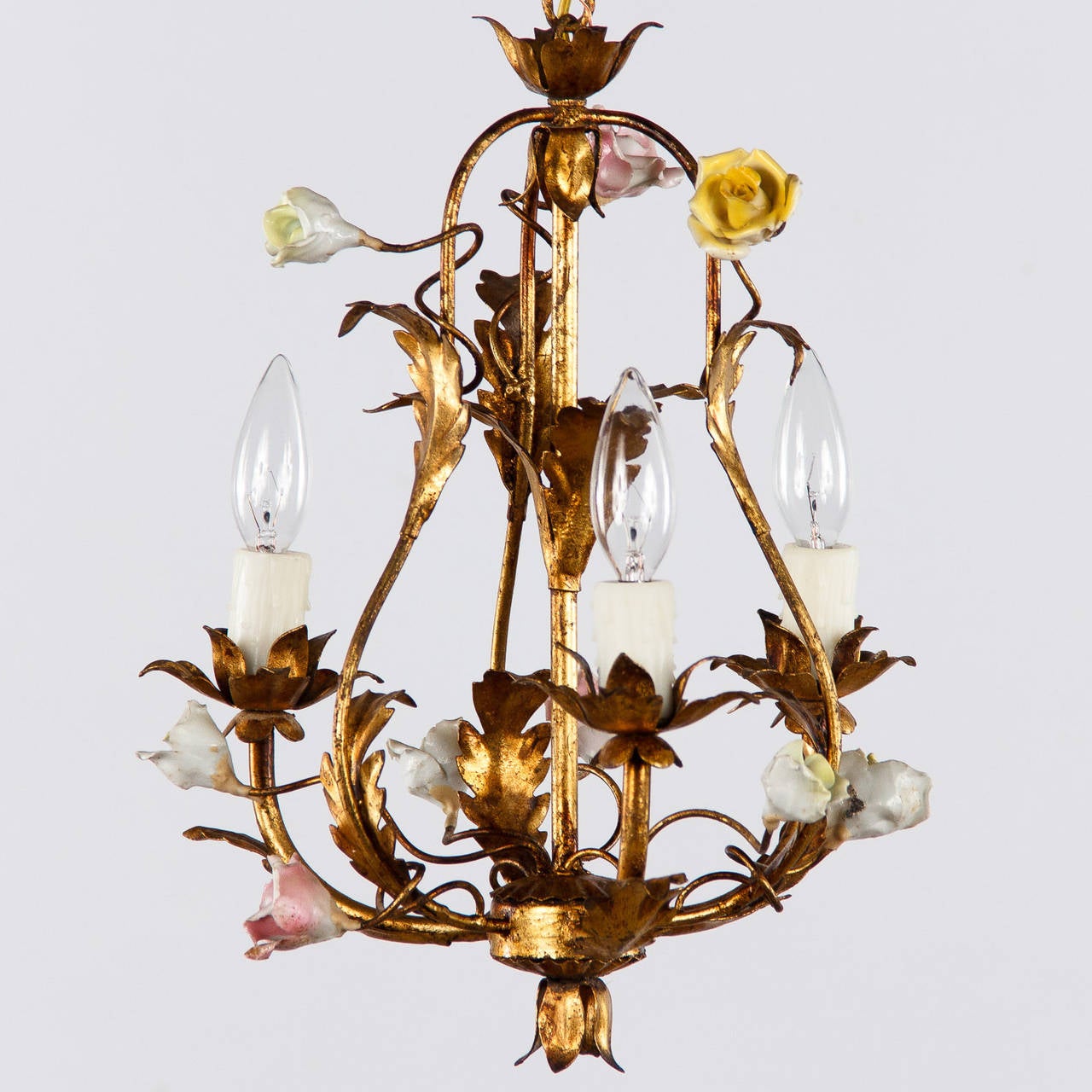 A romantic small Chandelier made of gilded tole with leaf motifs and porcelain roses. The fixture is housing 3 small socket bulbs up to 60w. each. The chain and canopy add 12.5