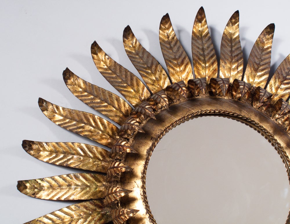 A stellar Spanish Mid-Century Sunburst Mirror with a gilded metal frame and leaf shaped rays. An eye-catcher!