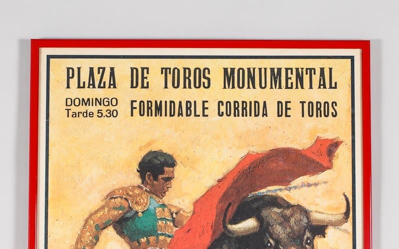 A Poster with a red metal frame advertising a bull fight in Barcelona, Spain.