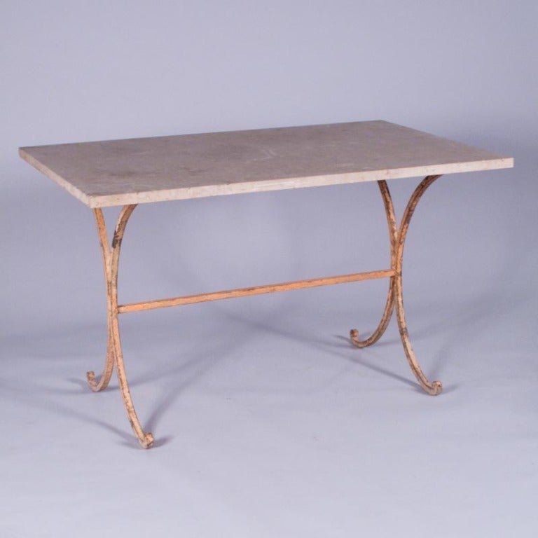 This 19th century Table de Jardin from the Provence Region has a beige travertine stone top. The iron base features scrolled and curved legs and was painted in distressed salmon tones.