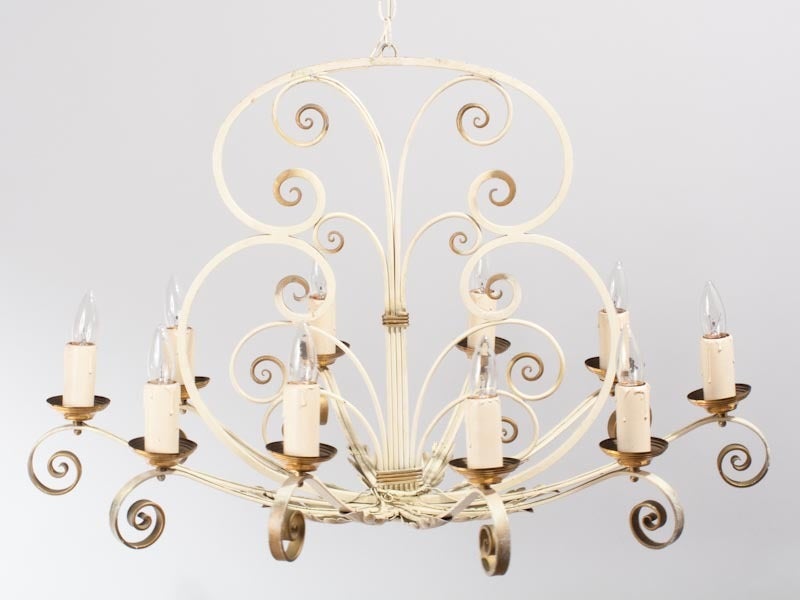 This 1940's French Chandelier is made of white painted metal, with copper accents and acanthus leaf and scroll motifs. It has 10 lights and is an oval shape which can work well over a kitchen island or dining table. Rewired to US Standards. With