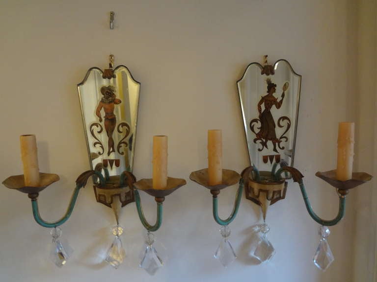 Chic pair of French 1940s Maison Jansen, Maison Badges, Robert Pansart style tole, églomisé (reverse decorated mirror) and crystal figural sconces. The commedia Del'Arte églomisé design is quite unusual and in great condition. These wall lights have