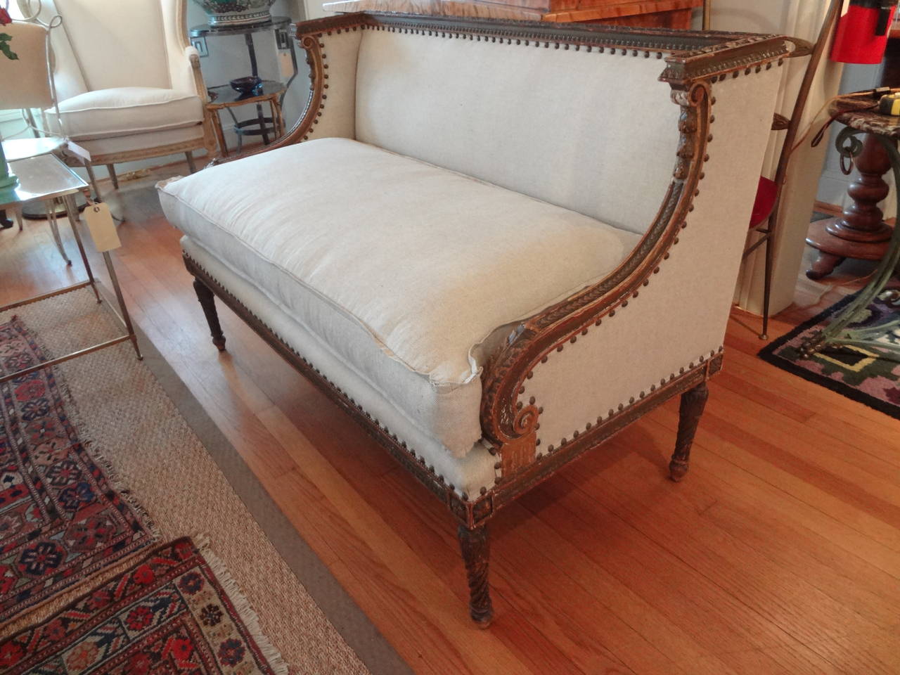 Unusually shaped French giltwood Directoire canapé or loveseat newly upholstered in oatmeal linen with spaced nailhead trim.