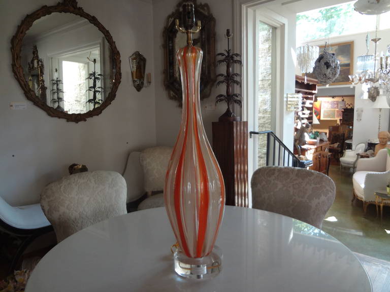 Lampe en verre de Murano de style moderne du milieu du siècle, d'une hauteur de 28,25 pouces, avec des rayures verticales orange et blanches alternées, montée sur une base en acrylique. Cette magnifique lampe en verre Murano de style Hollywood