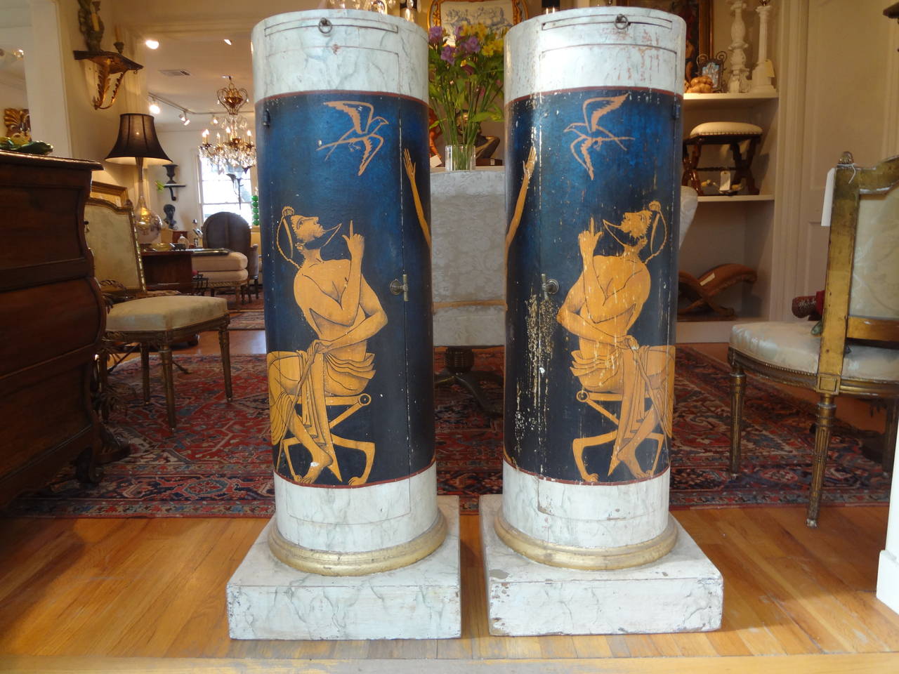 Outstanding pair of Italian neoclassical style painted and gilt column pedestals, each with cabinet door for storage and shelf and bronze hardware. (Dimensions: Base dimension 15.75 inches x 15.75 inches top 12.5 inches diameter).

