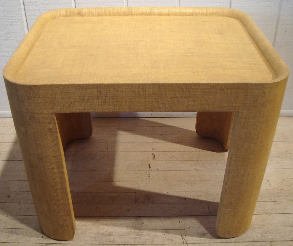 Wonderful and sculptural chunky signed Karl Springer side table completely covered in a wheat colored lacquered linen. Interesting concave legs with cut-out curved feet and integrated tray top. This piece retains its original stamped brass signature