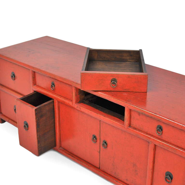 Red lacquer cupboard with nine drawers and two doors. Charming storage piece that also doubles as a bench.