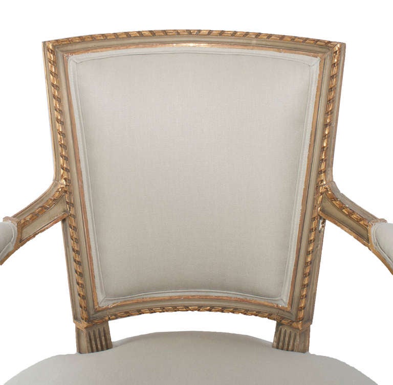 A set of four painted and gilt napoleon III fauteuils, seat and back are reconditioned and covered with new cotton and silk fabric. Wonderful patina on this set of gilt and grey painted Louis XVI style fauteuils. Padded armrests, tapered and fluted