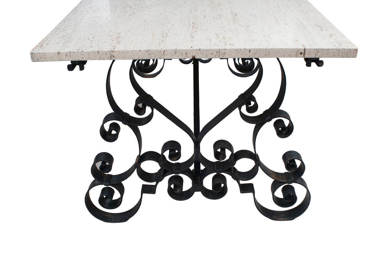 A cast iron table with a travertine top with two wooden extension leaves.