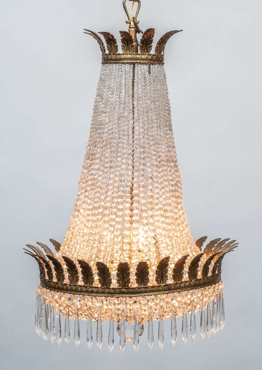 A crown of hand-cast acanthus leaves tops this chandelier - it has 9 internal lights - hand-cut crystal button prisms - fully restored in our shop - includes ceiling cap, appropriate chain and hanging hardware.