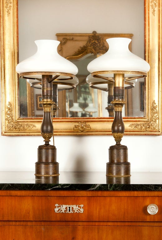 These lamps have excellent proportions and form - they were handmade by a master craftsman. The urns have classical motifs, as do the step bases. The white glass shades, while not original, are appropriate for the lamps.