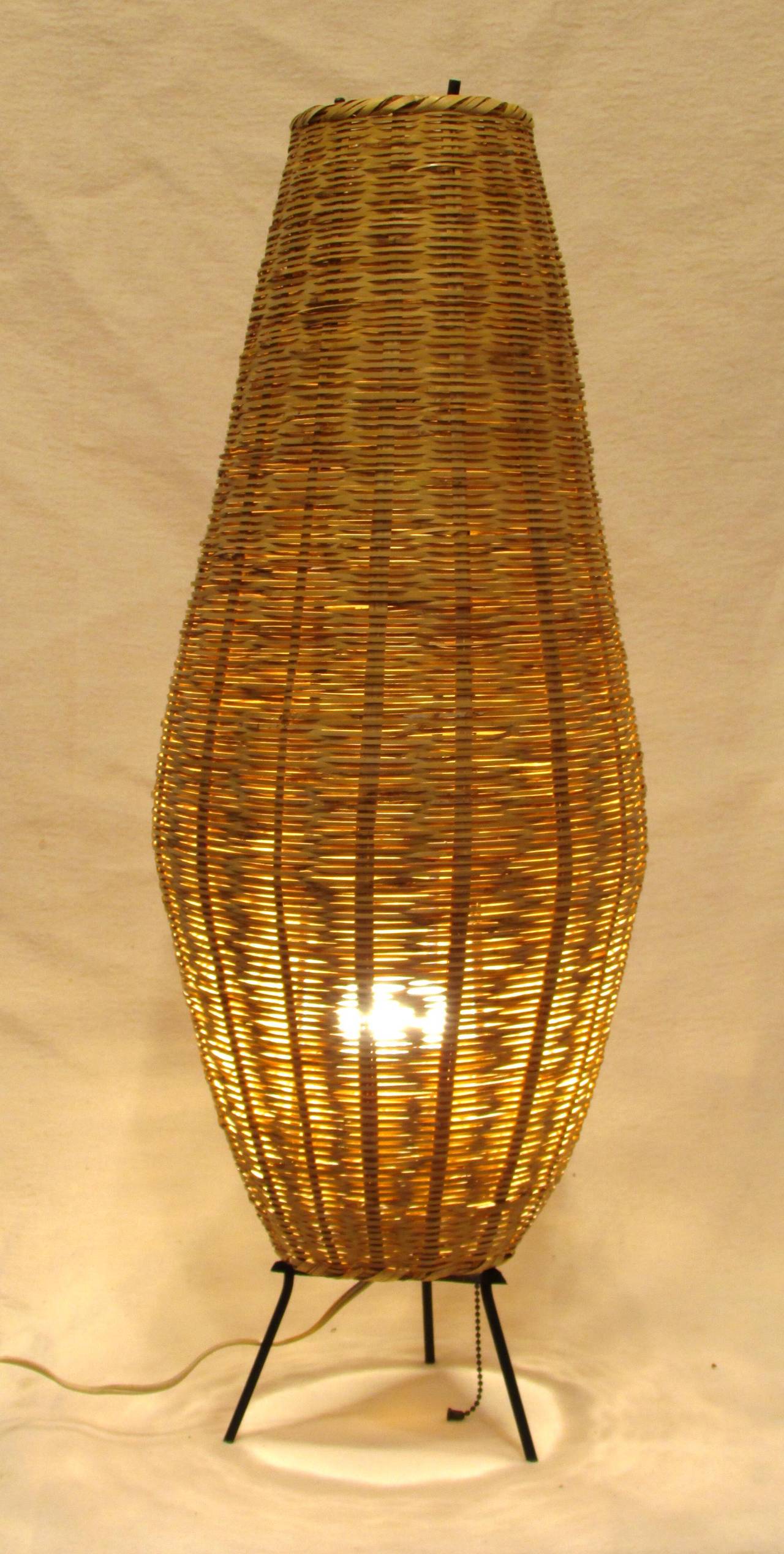 Tall oblong wicker basket over tripod metal lamp base these were made under a 1960's Peace Corp program in Ecuador using local craftsman to make scandinavian designed mid-century modern design furnishings