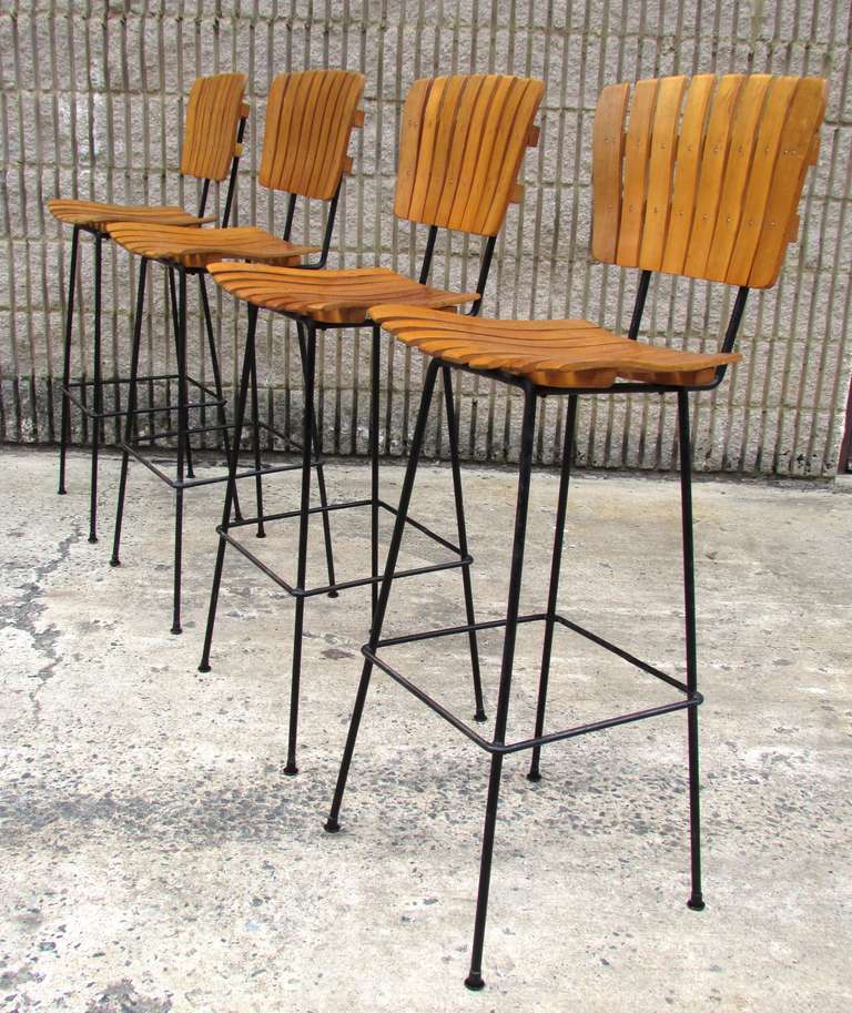 Set of four wrought iron and wood slate bar stools by Arthur Umanoff