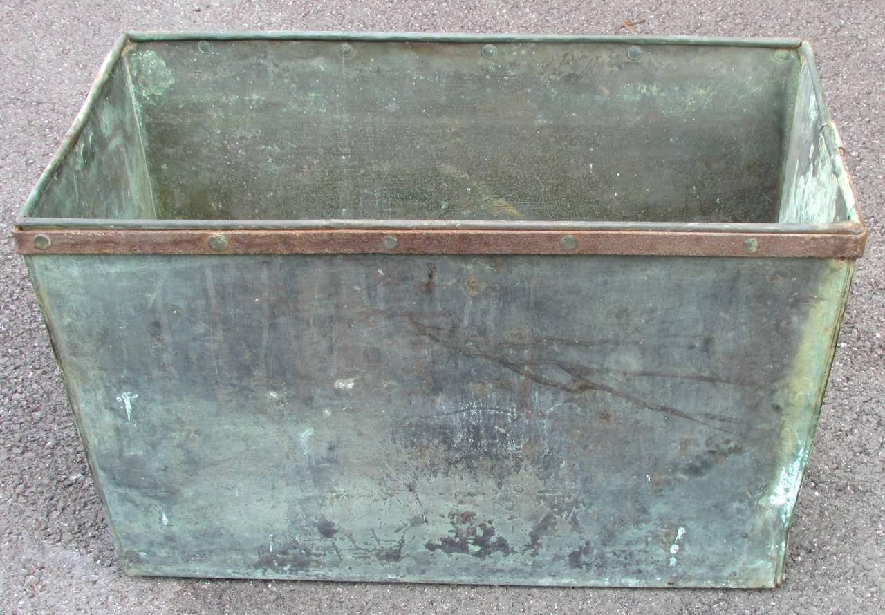 Old patinated copper box with iron handles from industrial setting now used as a planter box or for firewood