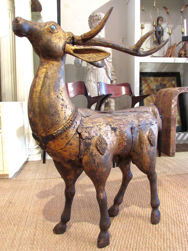 Large 19th century carved wooden and gilt standing stag deer from Indonesia with reflective metal eyes has beautiful worn and weathered patina.
