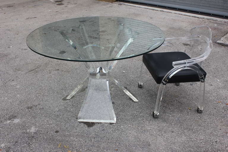Mid Century Modern Lucite Table and Chair Set. 4 Chairs on Rollers. Chairs have thick curved Lucite and Table has 3 Supports. Chairs are 32