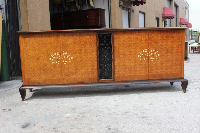 A French Art Deco Palisander buffet in the style of the Master Jules Leleu. Palisander marquetry, black opaline glass center panel, mother-of-pearl floral detail. Finished interior, all keys present.
