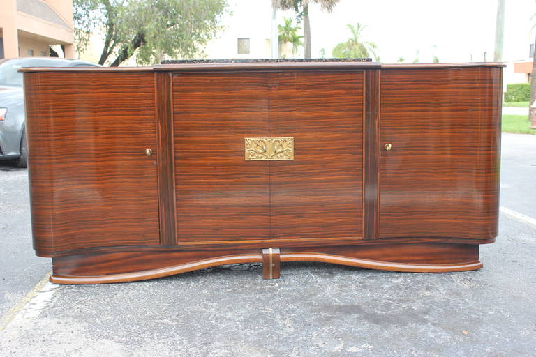 A Grand French Art Deco Designer Exotic Macassar Ebony Buffet, circa 1940's. This is an unsigned Sideboard. Center Bronze Plaque. Curved form. Finished interior, marble top.