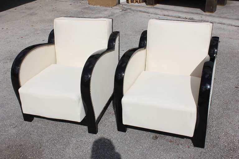 A pair of fantastic ebony gloss speed style club chairs that recline. Newly  upholstered in a synthetic off white textured vinyl fabric with nickel plated  nailhead trim.