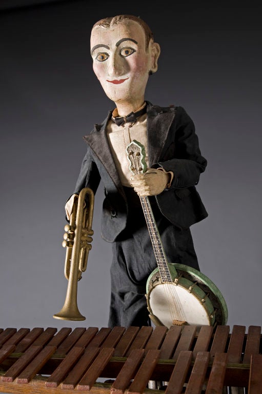 First quarter 20th century
Wooden puppet wearing cotton tuxedo, hand painted
face, one hand holds trumpet, other hand holds
banjo. Custom stand.
 Ex Mendelsohn Collection
Missing one hand.