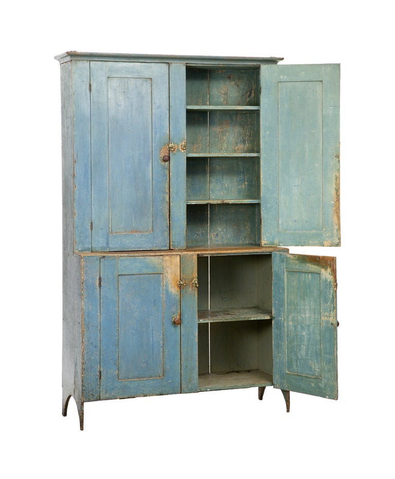 1830  
Original surface and condition except for pulls. 
Recessed front panel doors. Scrub top. Arched sides with delicate feet. Small cornice. Interior has three upper shelves, bottom has on shelf.