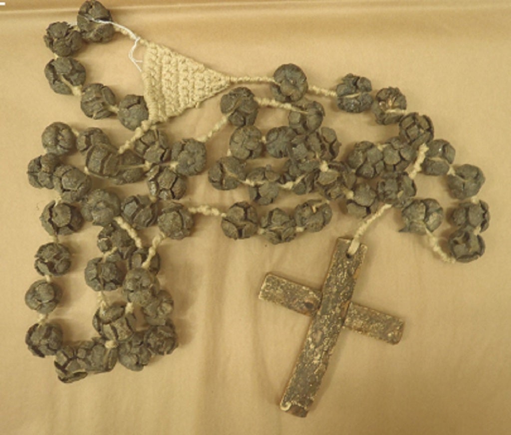 An oversized folk art rosary using wood,tree nuts and macrame.