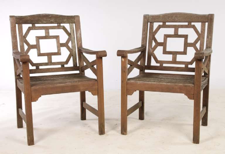 A pair of vintage Chinese Chippendale style teak garden chairs having fretwork back and x-form sides over slat seat. 
Dimensions: Ht: 36.5