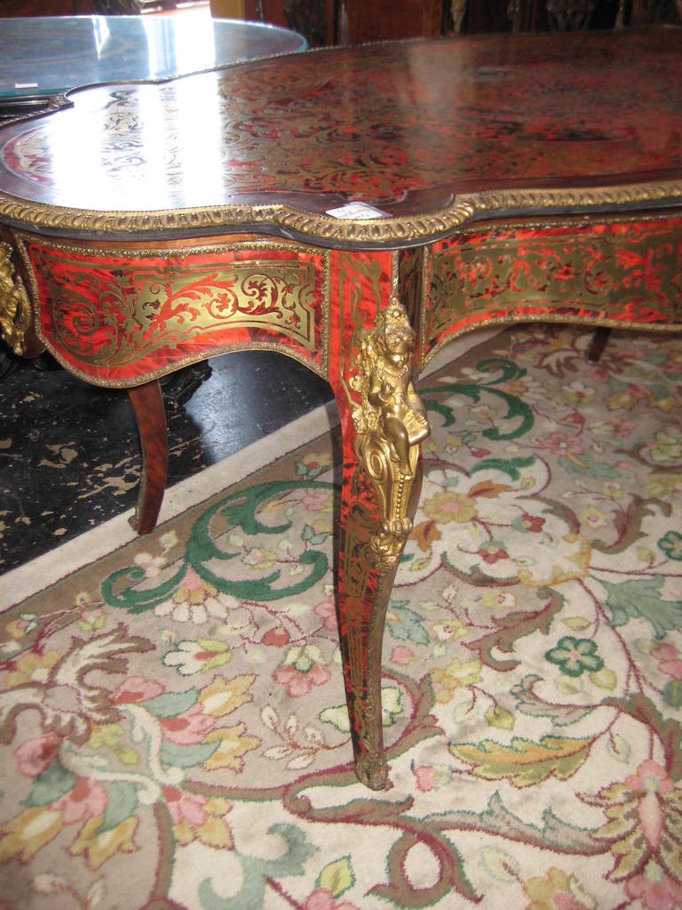 Napoleon III (1852-1873) Boulle center table, having a shaped oval top with bronze banded edge, inlaid with scroll and foliate strap work, the frieze also inlaid as the top and centering a mask, all on cabriole legs headed with female figural mounts