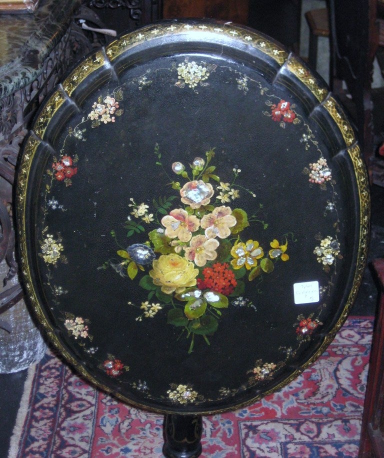 English Victorian papier mâché and mother-of-pearl inlaid tilt-top table, having a scalloped oval tilt-top, black lacquer and polychrome painted, baluster and ring turned standard joining a scalloped base on three feet.