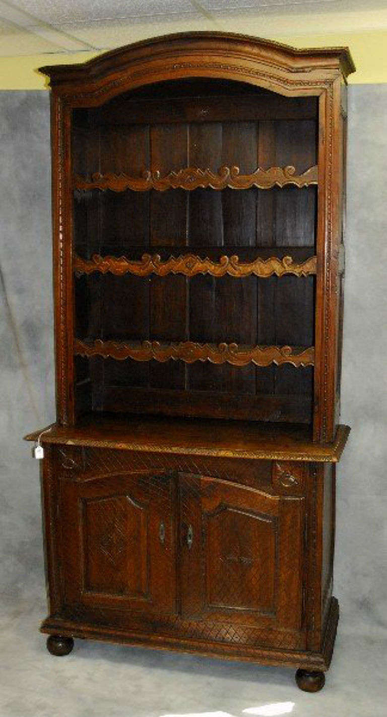 Provincial carved oak buffet deux corps, having a molded arch cornice over three open shelves with carved front rails above a pair of cabinet doors, molded base on bun feet.  H: 84