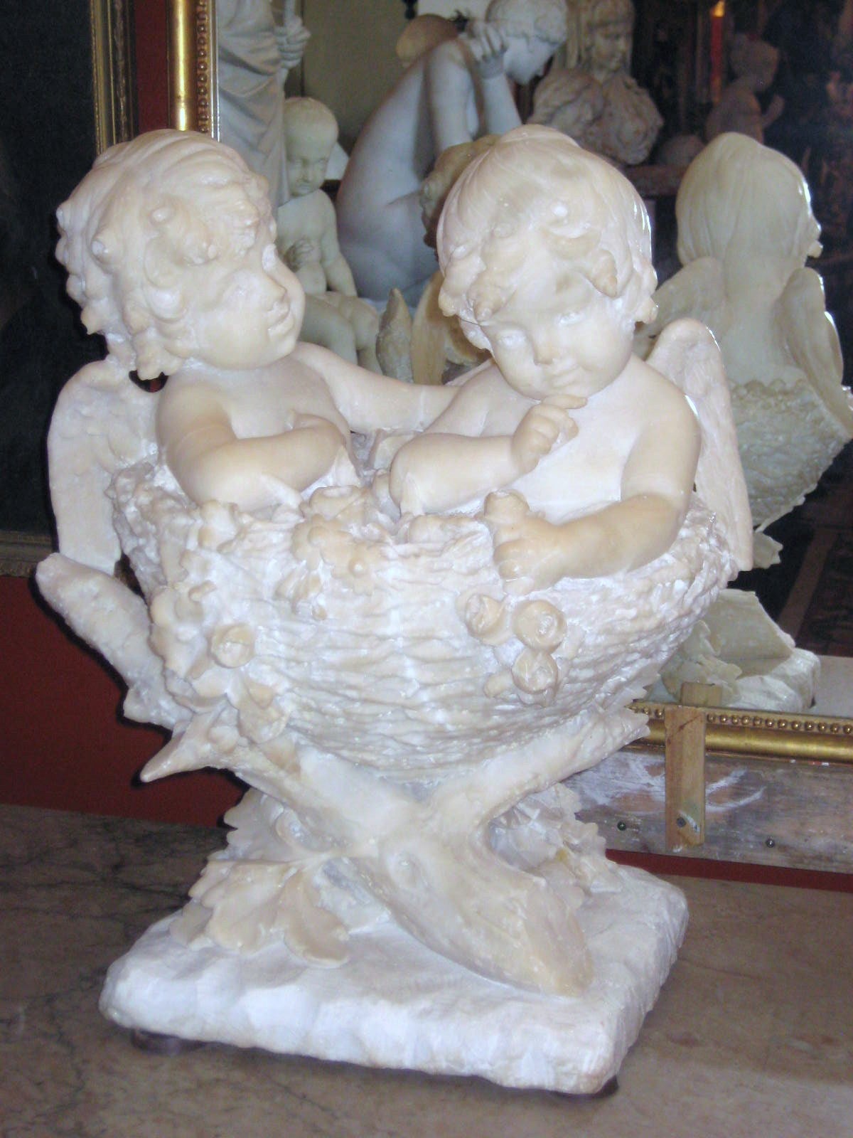 Continental carved marble group of two Angels seated in a basket of flowers