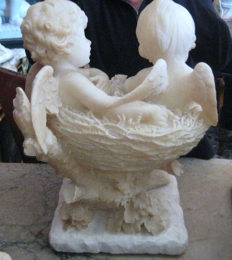 Continental carved marble group of two Angels seated in a basket of flowers, unsigned.
