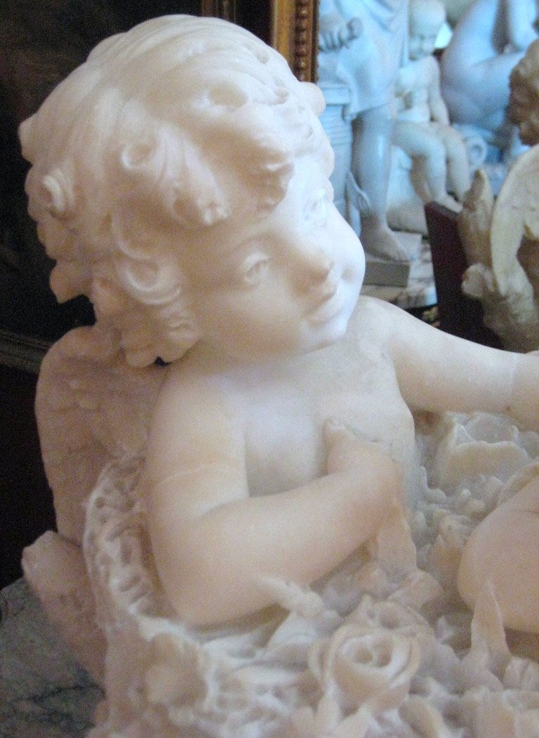 Italian Continental carved marble group of two Angels seated in a basket of flowers