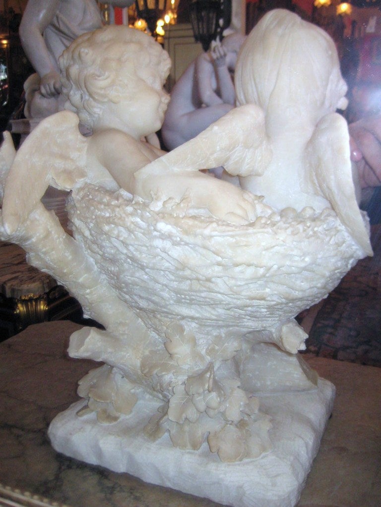 Marble Continental carved marble group of two Angels seated in a basket of flowers