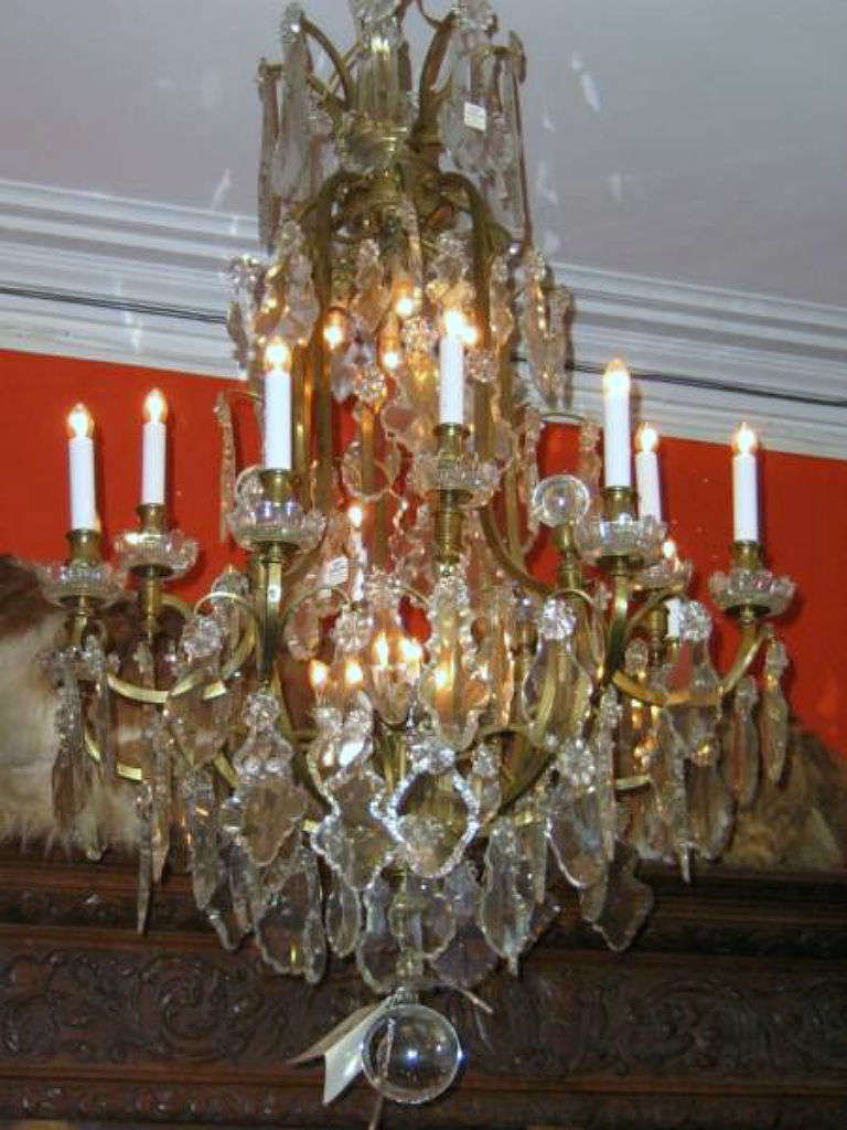 Louis XV bronze and crystal 12-light Baccarat style chandelier, having a bronze frame with 12 external candle branches with crystal bobesches, and hung throughout with rosettes, pendalogues and balls; the interior of the frame with four down