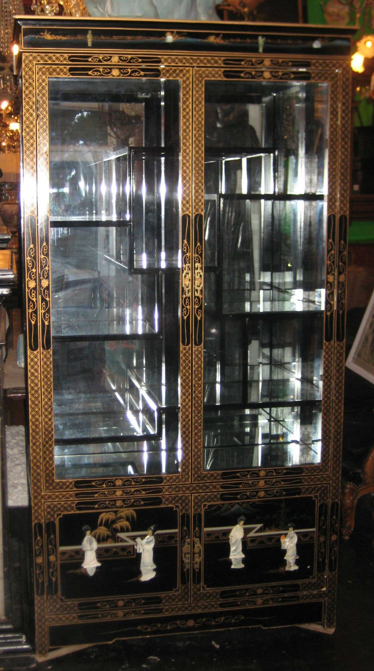 Chinese black lacquer, hardstone and gilt decorated collectors cabinet (curio cabinet), having two long glass and panel doors opening to an arrangement of staggerd shelves and lighted interior.