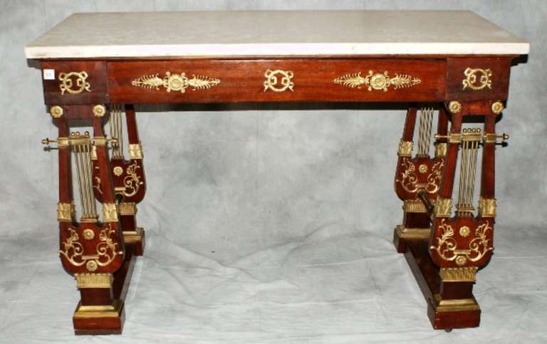 Empire mahogany bronze-mounted console table, the rectangular white marble top over a bronze-mounted frieze on double form legs with bronze mounts joining a trestle base.