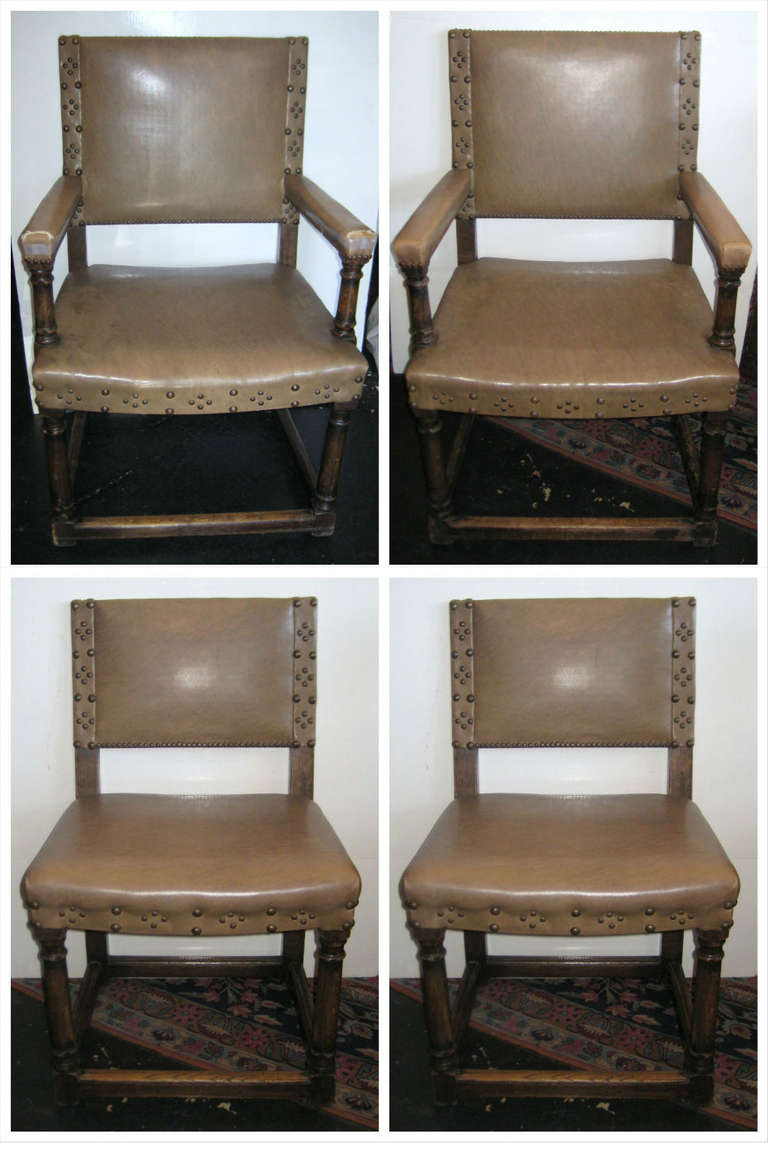 Set of ten Spanish colonial carved oak and leatherette dining chairs, comprising two-arm and eight side chairs, each with decorative nail heads, dowel construction.

Measures: Arm: H: 38.5