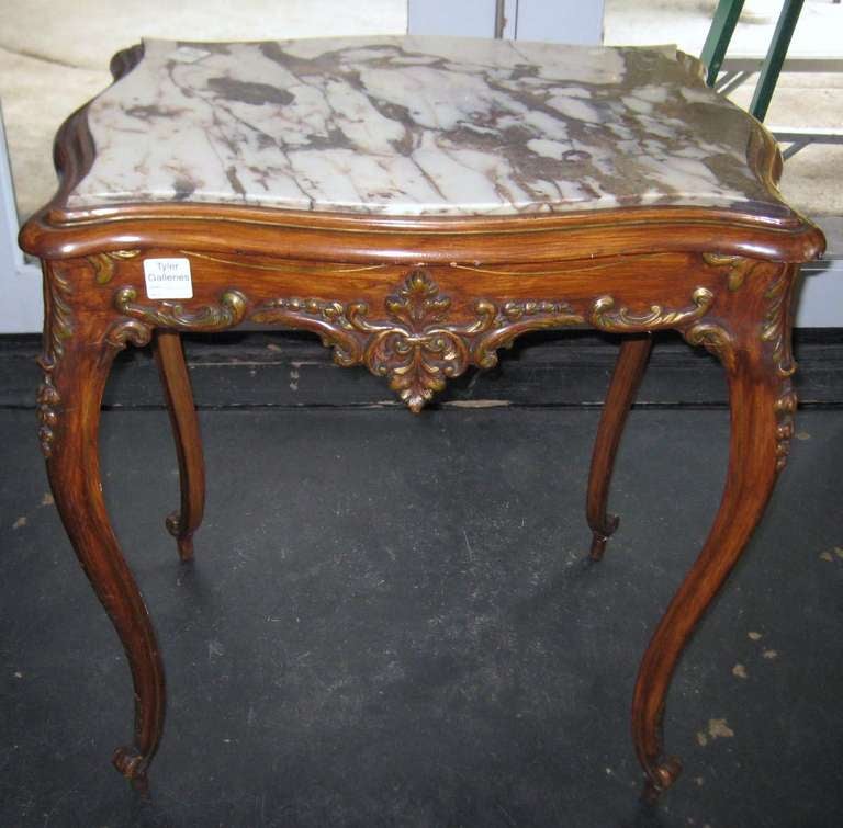 Louis XV style carved walnut and parcel gilt marble top table, having a shaped rectangular inset marble top above a scroll and foliate frieze on cabriole legs ending with knurl toe feet.