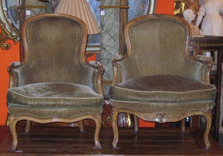 A near pair of Louis XV carved beechwood bergeres à la reine (of the period). One having a carved top and seat rail the other plain, hence near pair. Nevertheless, these are a wonderful pair of period Louis XV chairs. Each height at back: 37