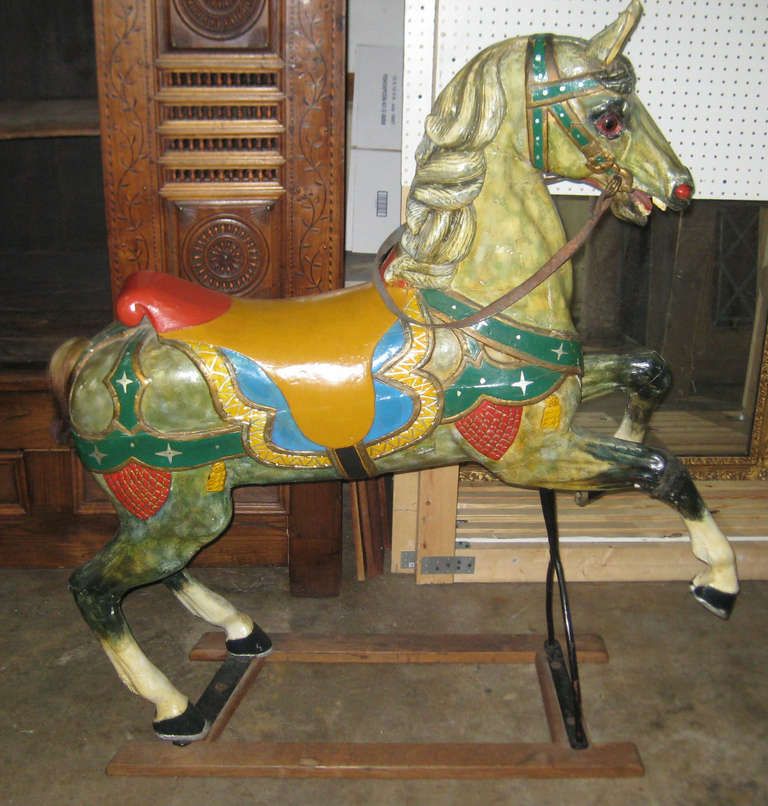 Antique prancing fixed position carousel horse decorated with carved mane, glass eyes and natural horse hair tail, original leather reins and beautifully painted. The underside has a stenciled number ten, which probably indicates position #10 of the