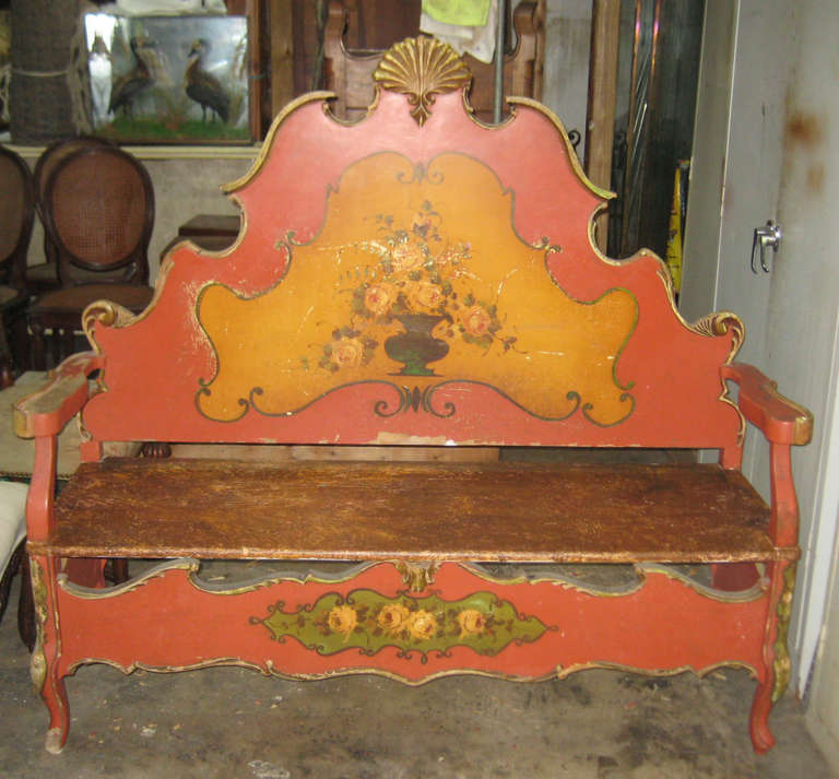 Italian carved and painted wood bench, having an arched scroll carved backrest with floral painted cartouch over a faux marbelized seat and scroll carved and painted front rail on cabriole legs.