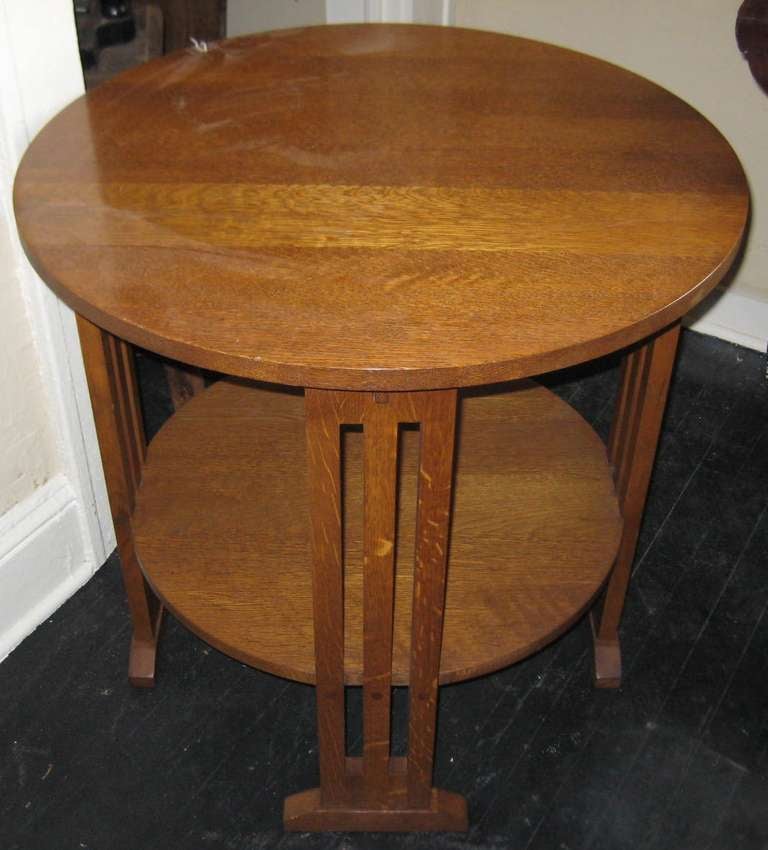 Stickley style oak lamp table with shelf, spindle ends and shoe foot.